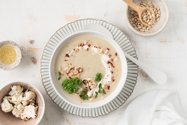 Foto gratuita sopa de crema de coliflor con nueces de pino en un cuenco sobre un fondo blanco