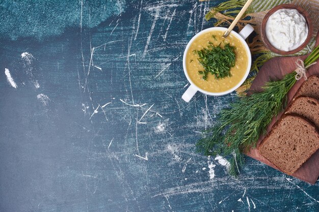 Sopa de crema con hierbas, crema agria y pan negro.