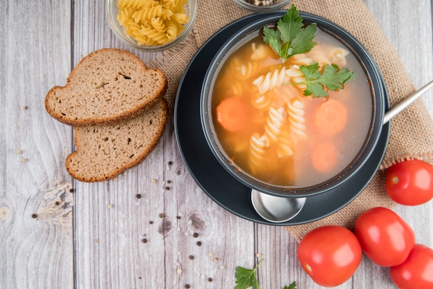 Sopa de diseño plano en un tazón con pan y tomates