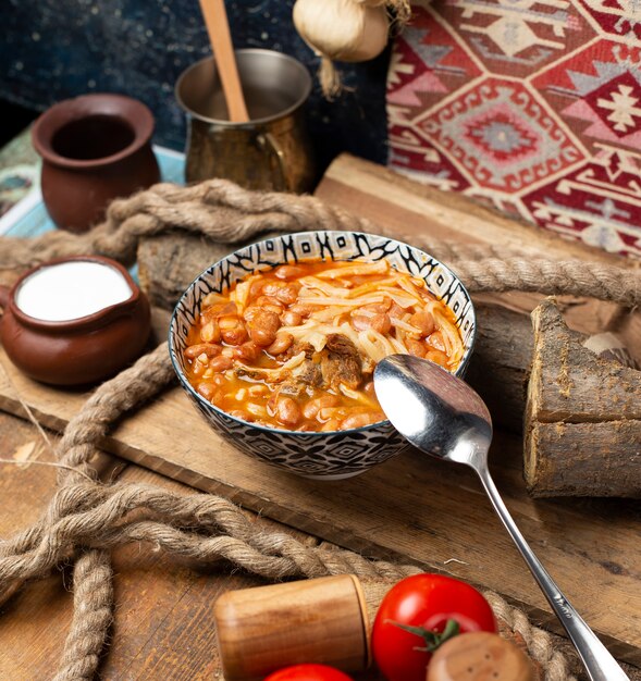 Sopa de fideos chinos con hierbas y especias en un tazón decorativo.