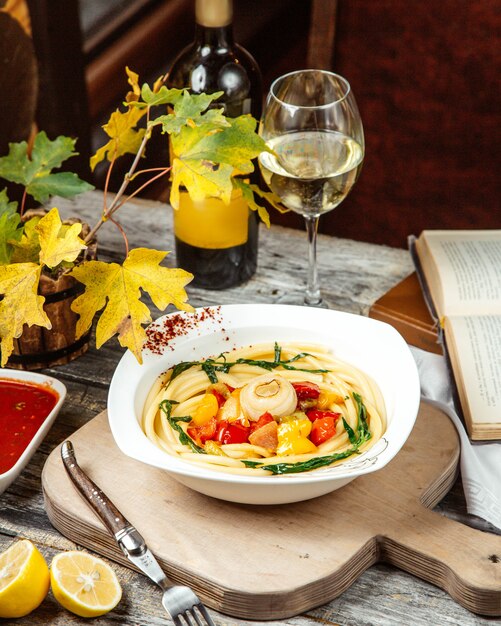 Una sopa con fideos y copa de vino.