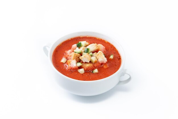 Sopa de gazpacho español tradicional en un recipiente aislado sobre fondo blanco.