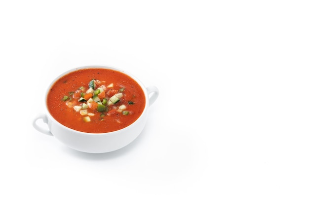 Sopa de gazpacho español tradicional en un recipiente aislado sobre fondo blanco.