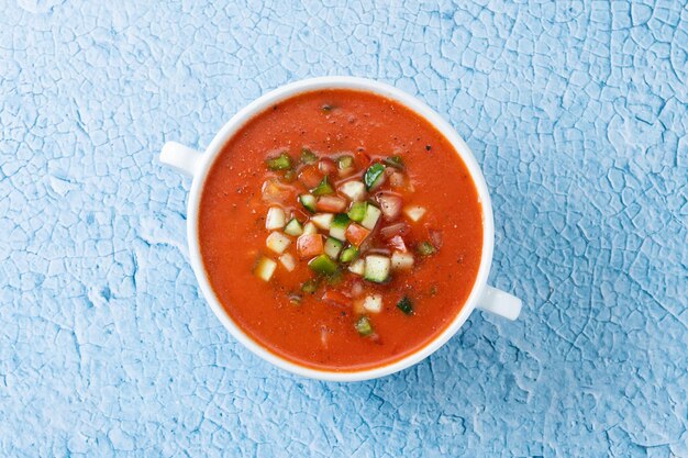 Foto gratuita sopa de gazpacho español tradicional en un tazón sobre fondo azul.