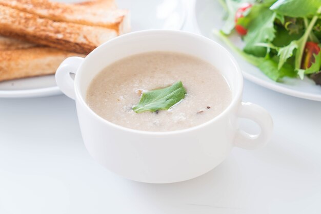 Sopa de hongos y pan en taza de cerámica blanca