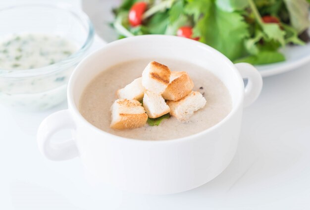 Sopa de hongos y pan en taza de cerámica blanca