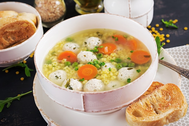 Sopa italiana de albóndigas y pasta Stelline en un tazón sobre la mesa negra. Sopa dietética Menú para bebés Comida sabrosa.