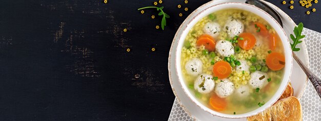 Sopa italiana de albóndigas y pasta Stelline en un tazón sobre mesa negra