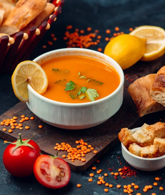 Sopa de lentejas rojas con una rodaja de limón y pan rallado