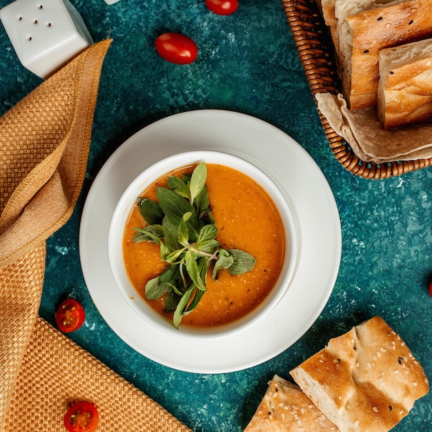 Sopa de lentejas en un tazón blanco y hierbas