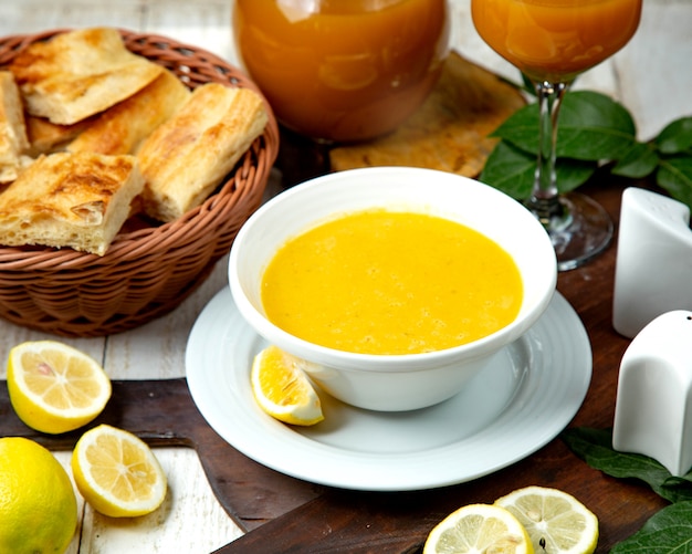 Sopa de lentejas en un tazón blanco y una rodaja de limón