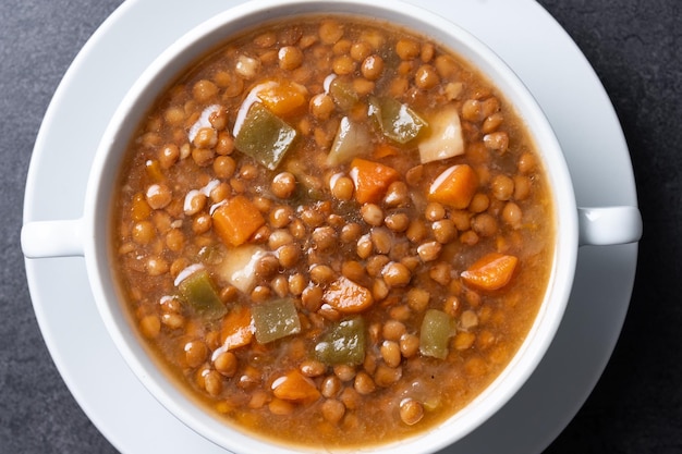 Sopa de lentejas con verduras en un cuenco sobre un fondo negro