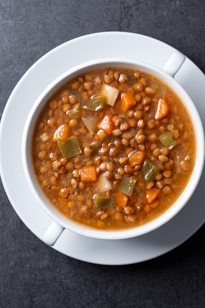 Sopa de lentejas con verduras en un cuenco sobre un fondo negro