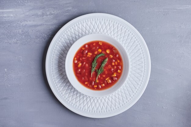 Sopa de maíz en salsa de tomate en un tazón blanco.