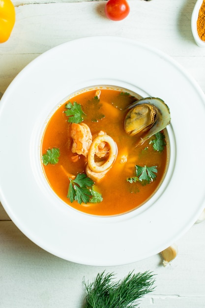 sopa de mejillones con tomate y hierbas en un tazón blanco