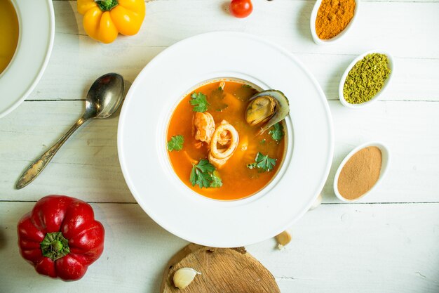 sopa de mejillones con tomate y hierbas en un tazón blanco