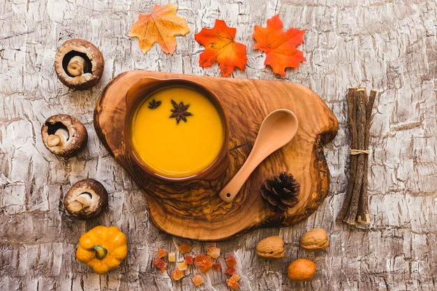 Foto gratuita sopa en pedazo de madera cerca de símbolos de otoño