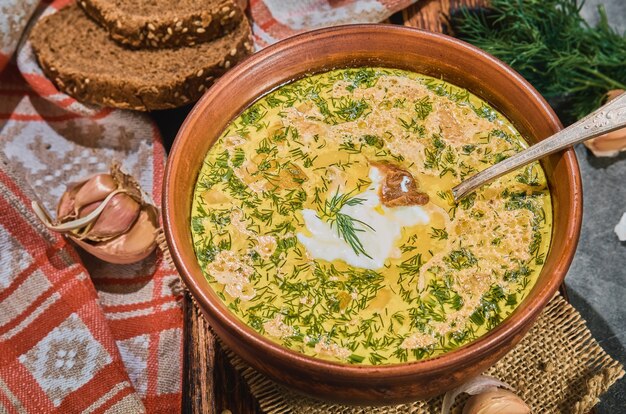 Sopa de pescado con verduras y setas y carne de pollo, primer plano con enfoque selectivo. El plato hondo se sirve con pan negro, crema agria y ajo. Un saludable almuerzo de invierno.