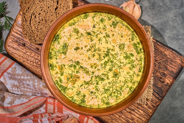 Sopa de pollo con verduras y setas, vista superior, primer plano. Servido con pan negro y ajo. Un saludable almuerzo de invierno. Diseño sobre fondo gris