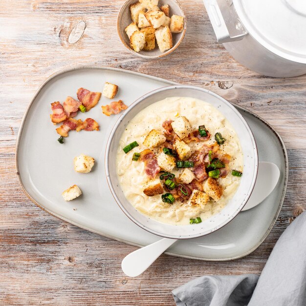 Sopa de queso con crutones y tocino en un bol sobre una mesa de madera