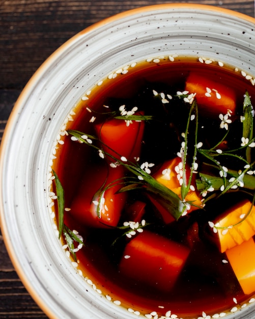 Sopa servida con verduras y semillas.