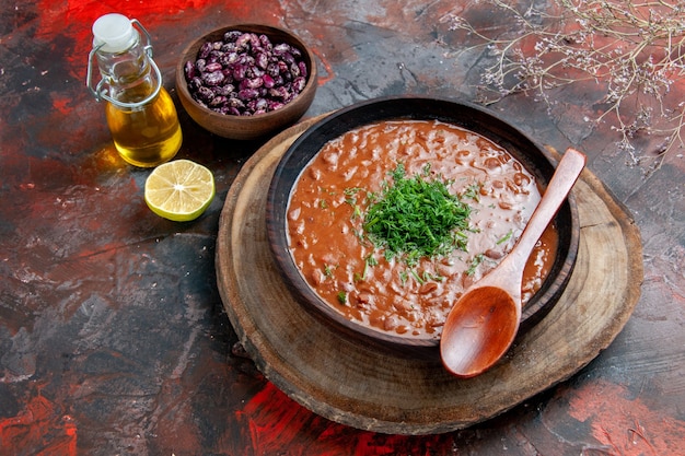 Sopa de tomate clásica en una botella de aceite de cuenco marrón frijoles y cuchara en la mesa de colores mezclados