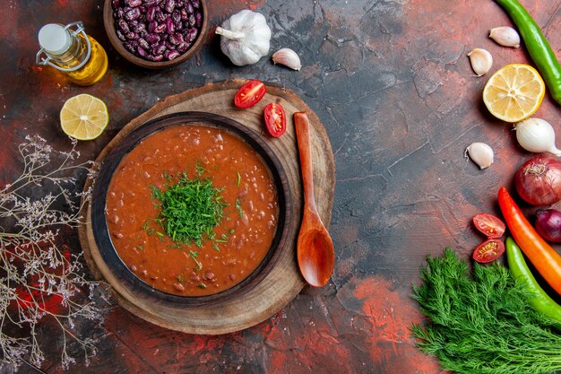 Sopa de tomate clásica en una botella de aceite de cuenco marrón frijoles y cuchara en la mesa de colores mezclados