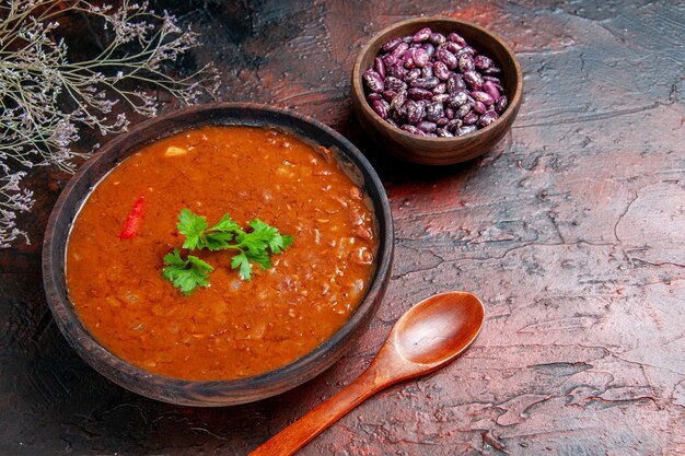 Sopa de tomate clásica en un cuenco marrón frijoles y cuchara en la mesa de colores mezclados