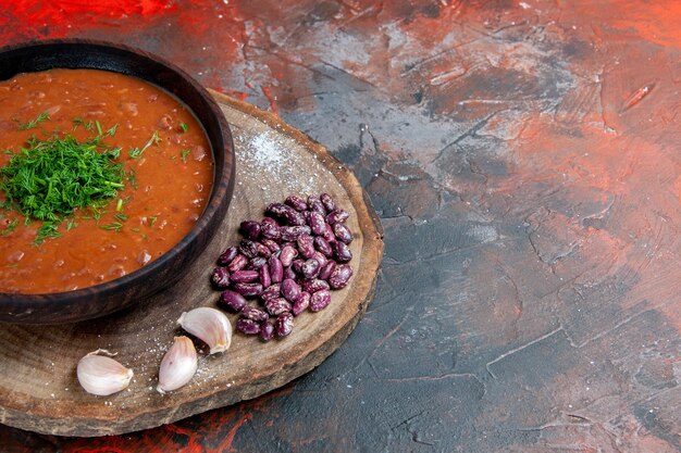 Sopa de tomate, frijoles, ajo sobre la tabla de cortar de madera en la mesa de mezcla de colores