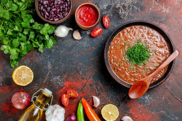 Sopa de tomate con un manojo de ajo verde botella de aceite y una cuchara en la mesa de colores mezclados