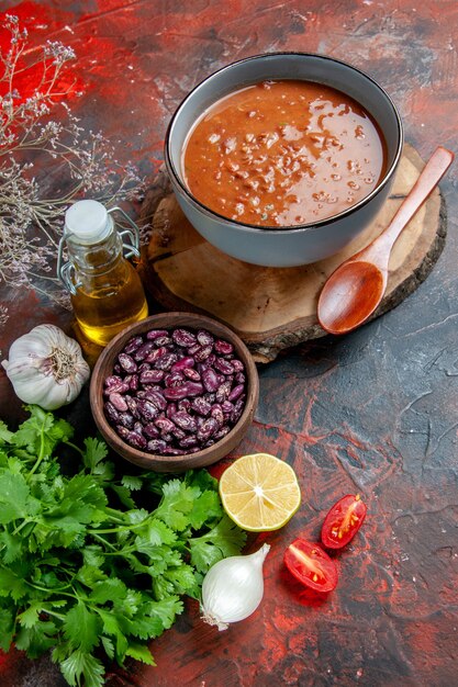 Sopa de tomate en un recipiente azul en una bandeja de madera botella de aceite de frijoles en la tabla de colores mezclados