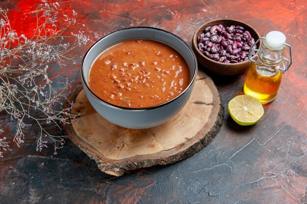 Sopa de tomate en un recipiente azul en una bandeja de madera marrón botella de aceite de frijoles en la tabla de colores mezclados