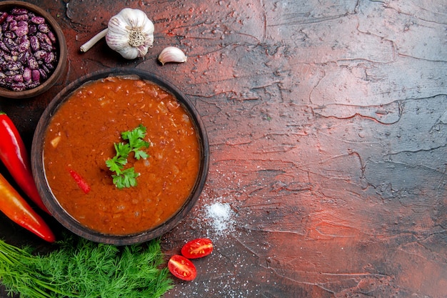 Sopa de tomate en un recipiente marrón y diferentes especias ajo limón en imágenes de mesa de colores mezclados