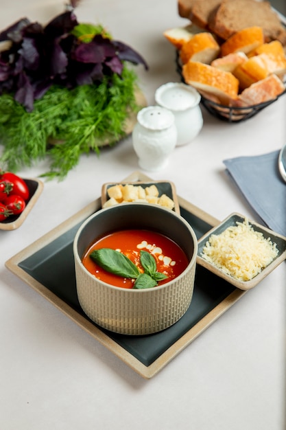 sopa de tomate servida con queso rallado y galletas saladas