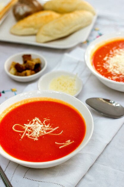 Sopa de tomate servida con queso rallado y galletas