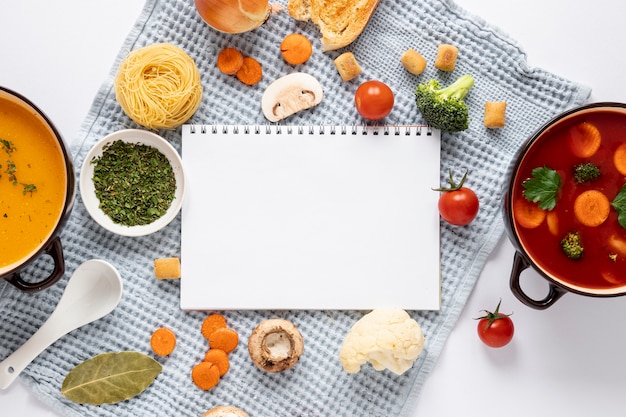 Sopa de tomate y verduras con bloc de notas vacío