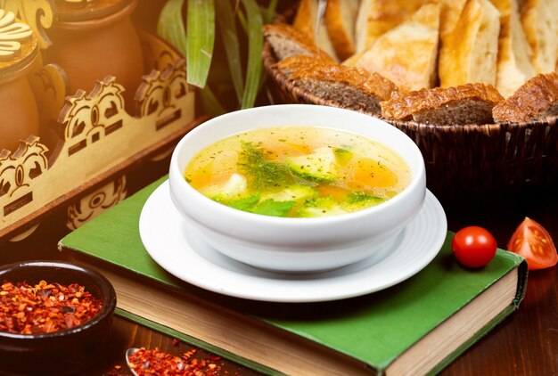 Sopa de verduras casera de pollo, vista desde arriba sobre un libro sobre la mesa