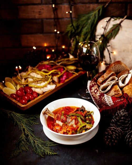 Sopa de verduras con encurtidos y copa de vino.