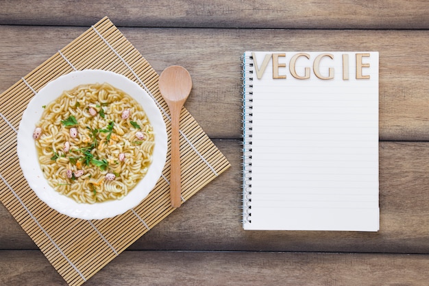 Sopa de verduras junto a las letras de verduras en el cuaderno