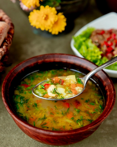 Sopa de verduras servida con hierbas.