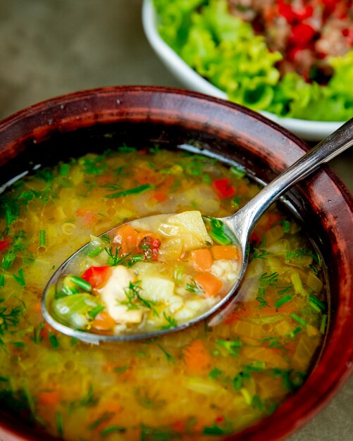 Sopa de verduras servida con hierbas.