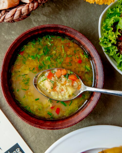 Sopa de verduras servida con hierbas.