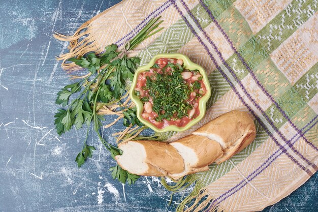 Sopa de verduras servida con pan baguette, vista superior.