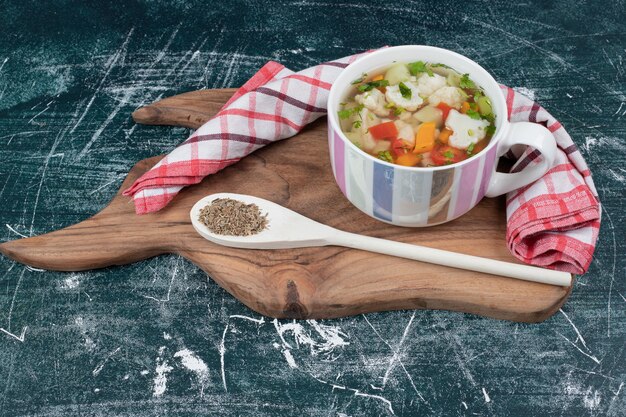 Sopa de verduras sobre tabla de madera con mantel y cuchara. Foto de alta calidad