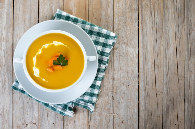 Sopa de zanahoria con crema y perejil sobre mesa de madera