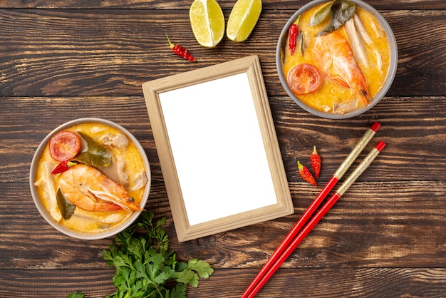 Sopas de alto ángulo en tazones con camarones limón y palillos con marco en blanco