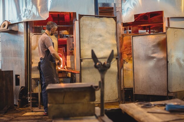 Soplador de vidrio calentando un vaso en horno de sopladores de vidrio