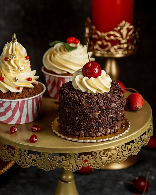 Soporte de tarta con pastel de cereza de chocolate y cupcakes