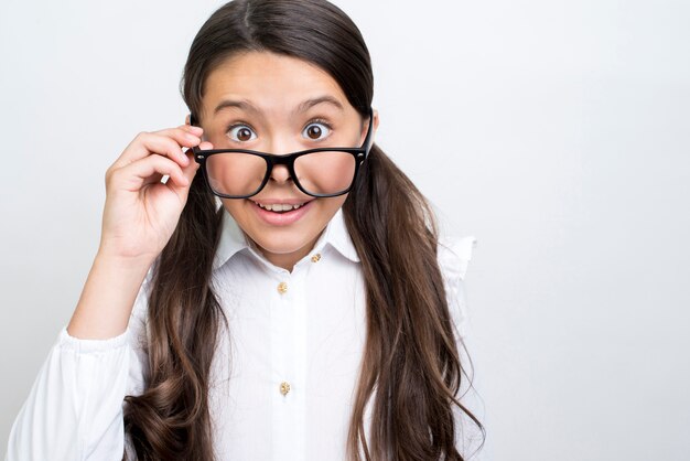 Sorprendida colegiala hispana enderezar gafas.