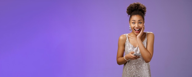 Foto gratuita sorprendida emocionada guapa mujer afroamericana en vestido plateado brillante tocar palma asombrada wi